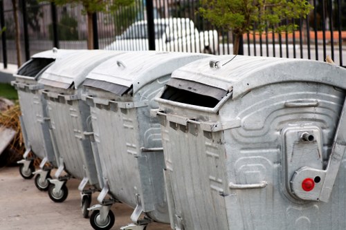 Uniformed crew handling commercial waste bins on a Shepherds Bush street